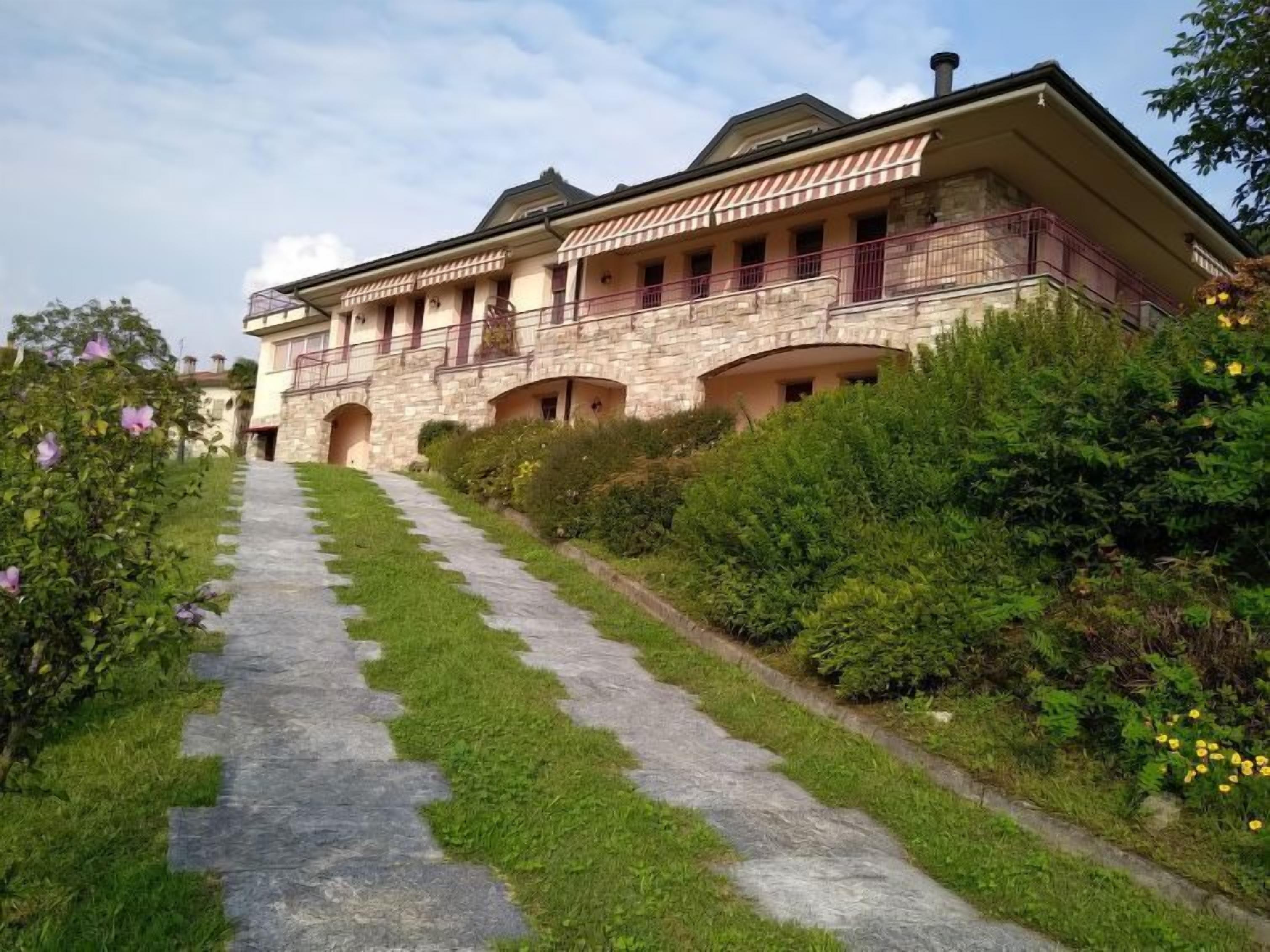 A stone building with a central courtyard, multiple balconies, and a pathway leading to the entrance.