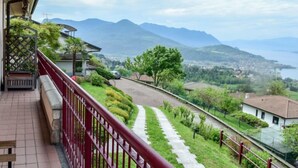 A balcony with a red railing overlooking a mountainous landscape and a body of water. - Achillea by Interhome (Luino)