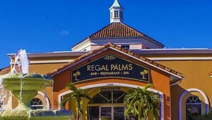 Un edificio con un letrero que dice "Regal Palms Bar, Restaurant, Spa" y una fuente en la parte delantera.