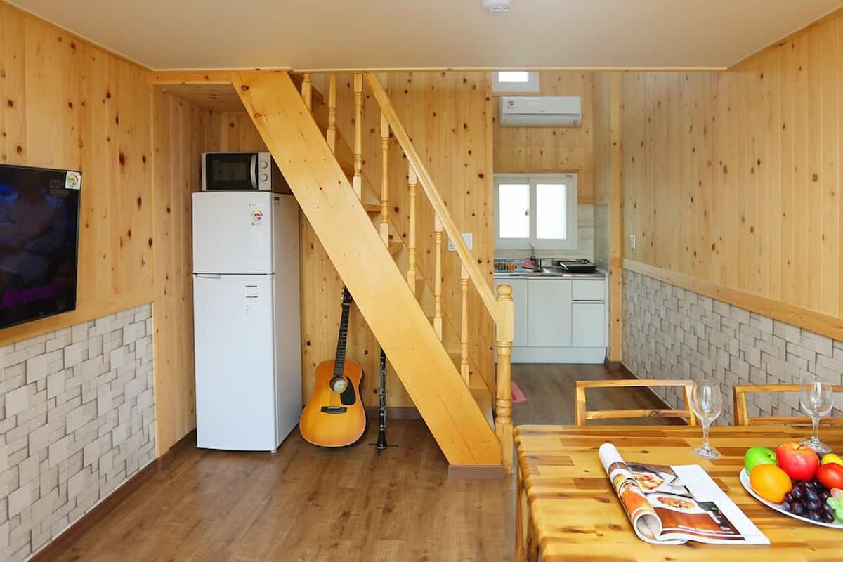 Interior de madera con cocina, comedor y escalera.