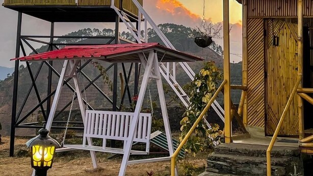 A two-story wooden building with a balcony and a staircase leading to the upper level. - BSR Farms (Pauri)