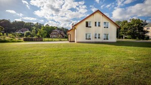 Une maison à deux étages avec un toit en pente, une pelouse devant et un ciel dégagé.