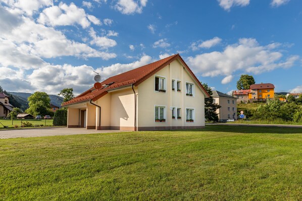 A two-story house with a red roof, a front porch, and a well-maintained lawn. - Apartment in the Ore Mountains / Karlovy Vary region UNESCO (Ostrov)