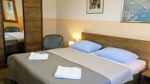 Un lit bien fait, avec deux oreillers et deux serviettes pliées, une lampe de chevet, une chaise et un tableau accroché au mur.