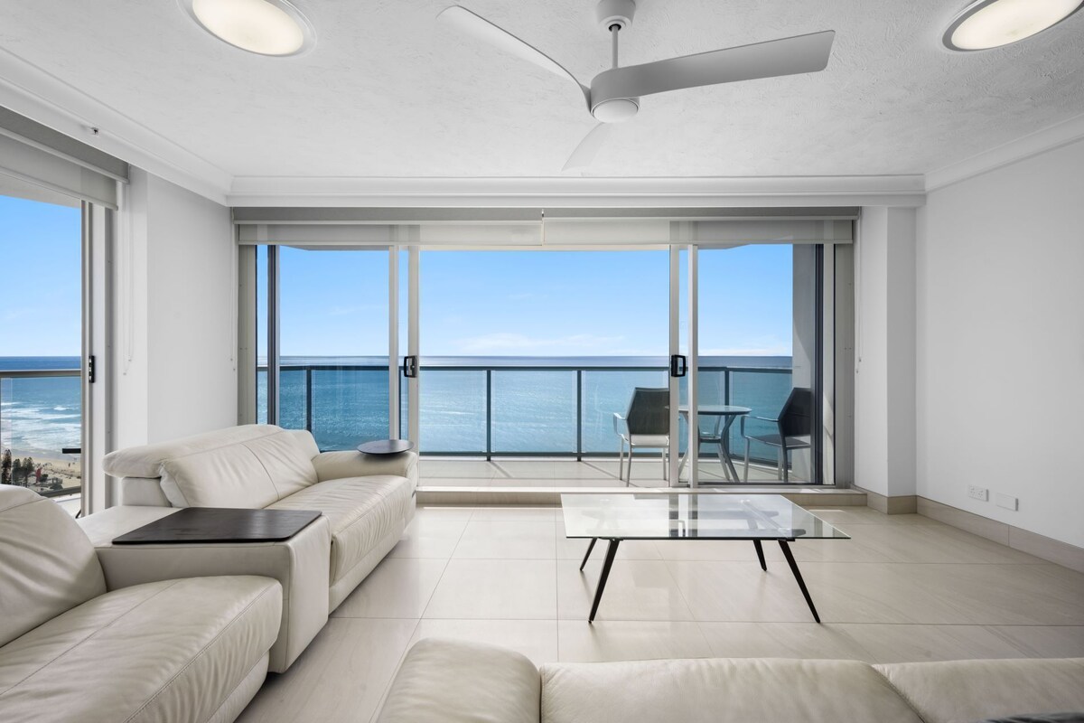 A spacious living room with a large sliding glass door leading to a balcony with ocean views.