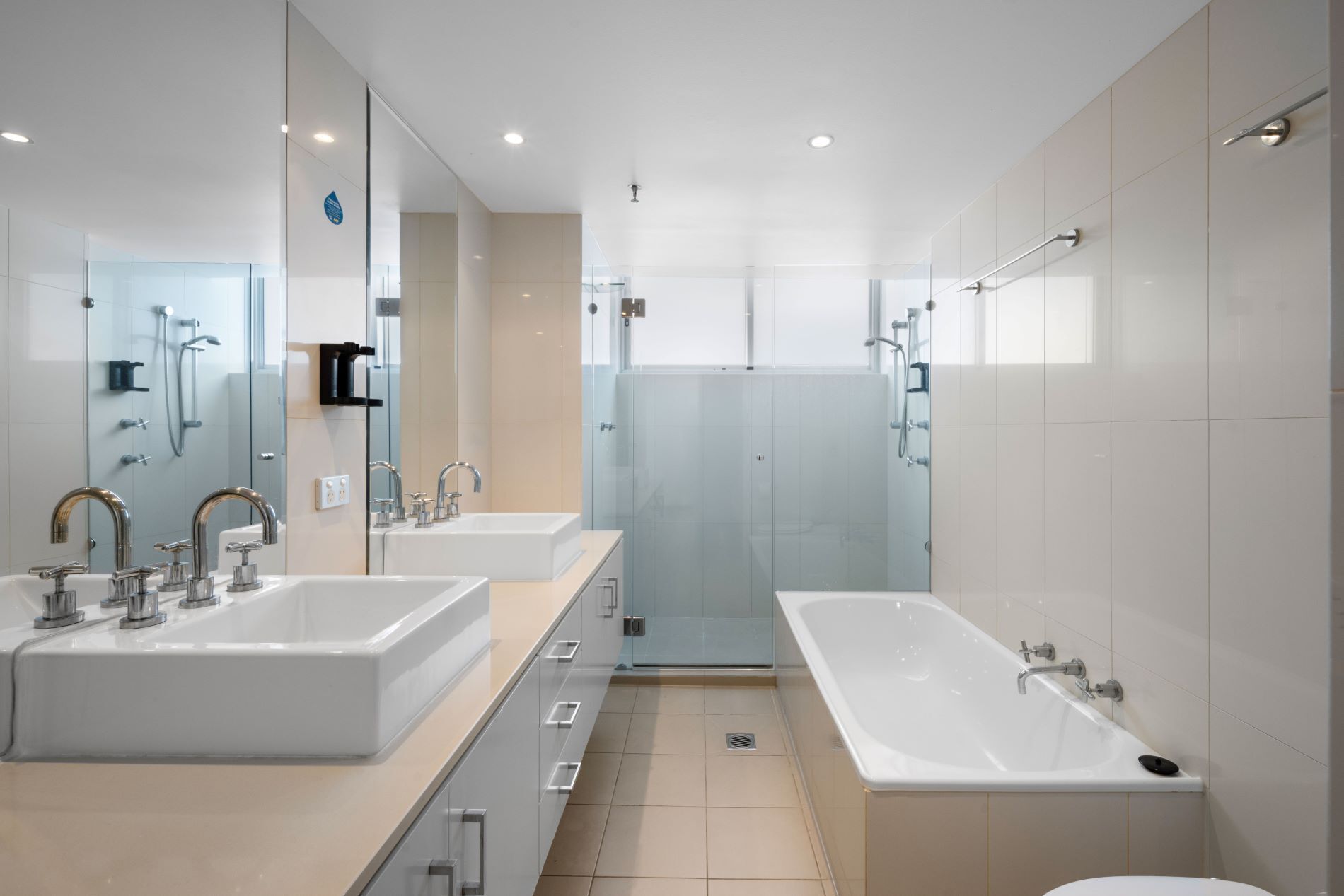 A modern bathroom with two sinks, a bathtub, and a shower area.