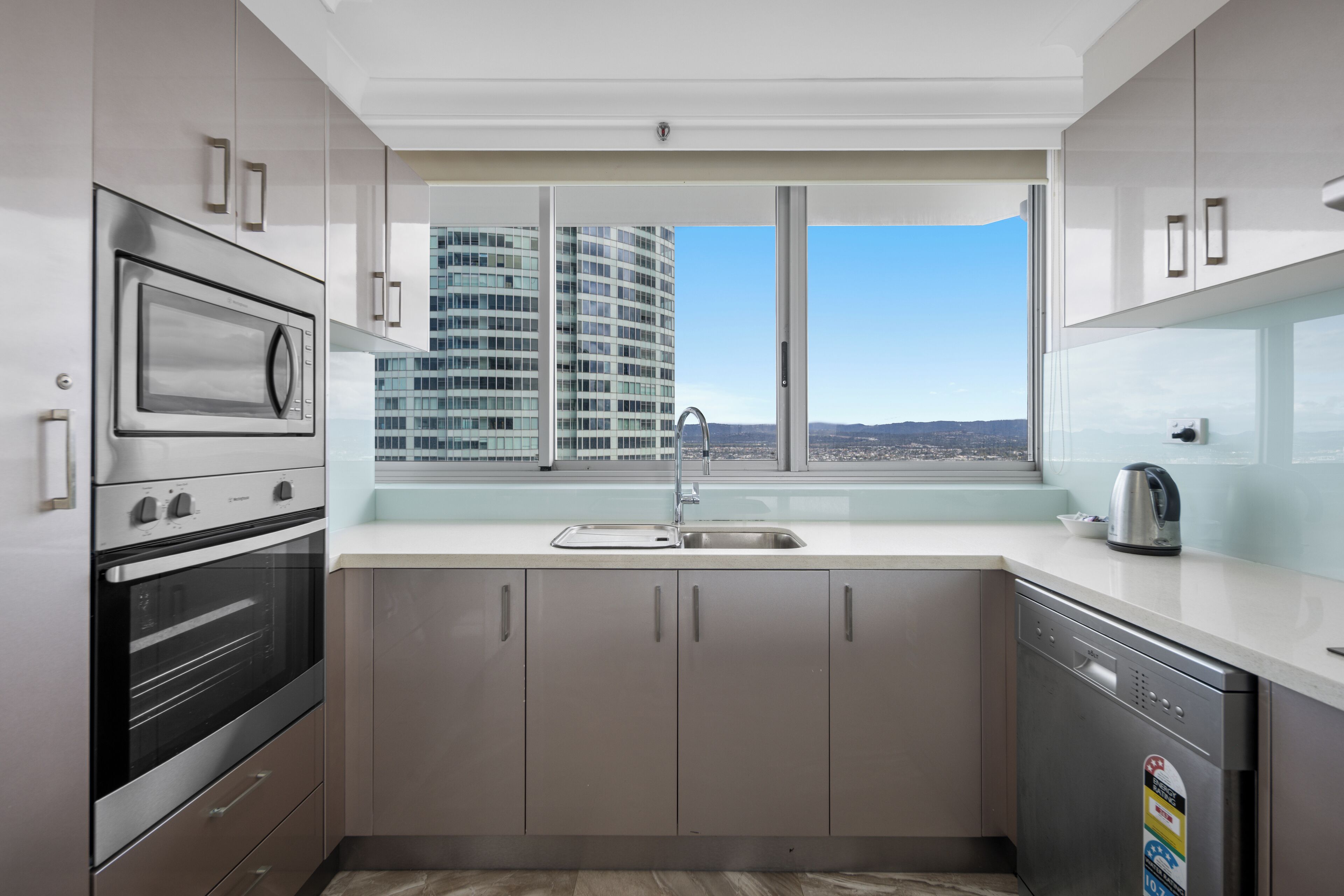 A modern kitchen with stainless steel appliances, a large window, and a view of a cityscape.