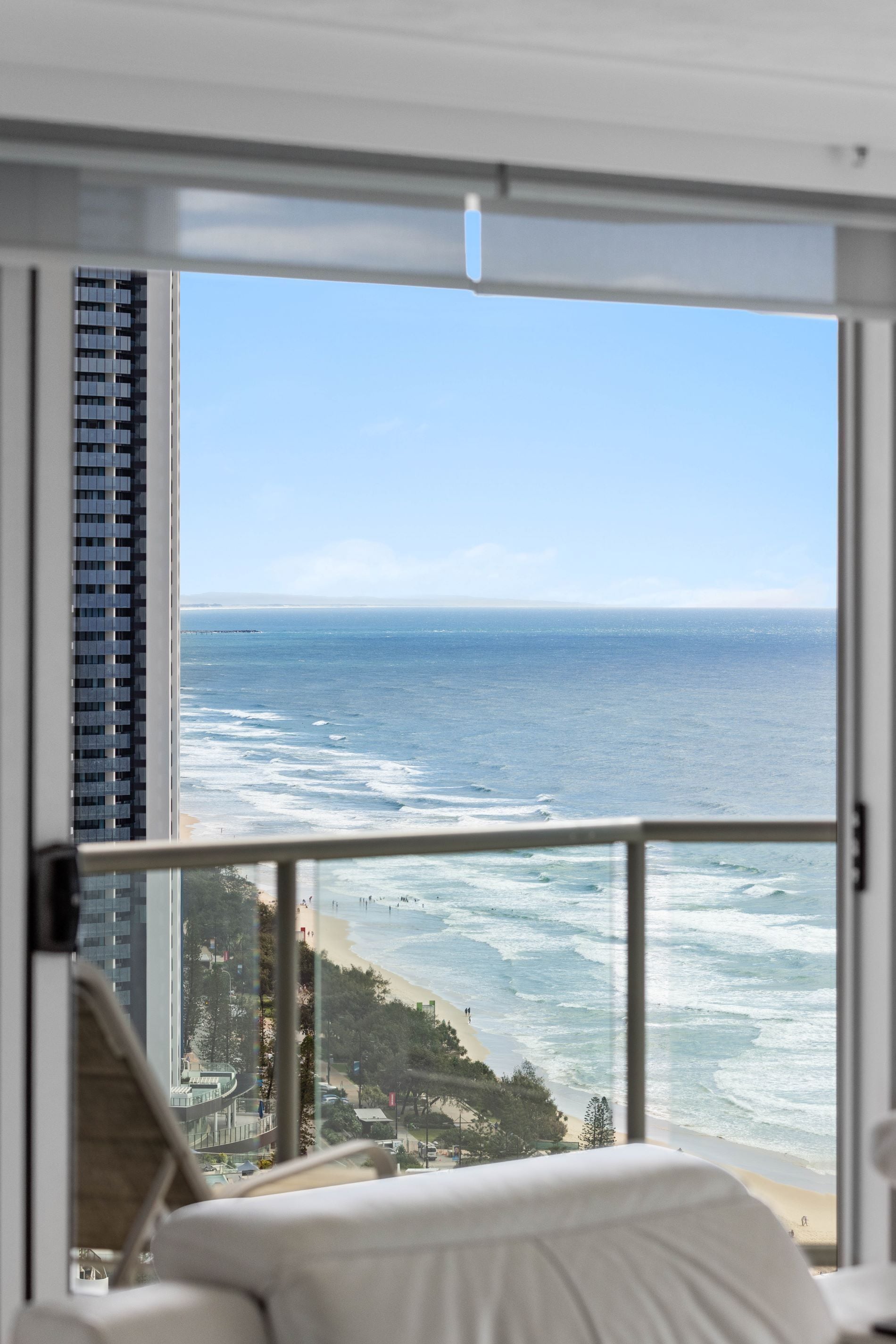Habitación de hotel con un amplio ventanal con vista a una playa y al océano.