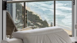 A hotel room with a large window overlooking a beach and ocean. - Peninsula Resort - Private Apartments (Surfers Paradise)
