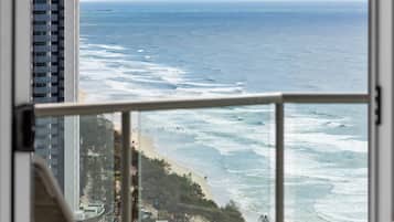 Habitación de hotel con un amplio ventanal con vista a una playa y al océano.
