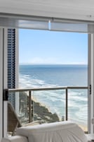 Habitación de hotel con un amplio ventanal con vista a una playa y al océano.