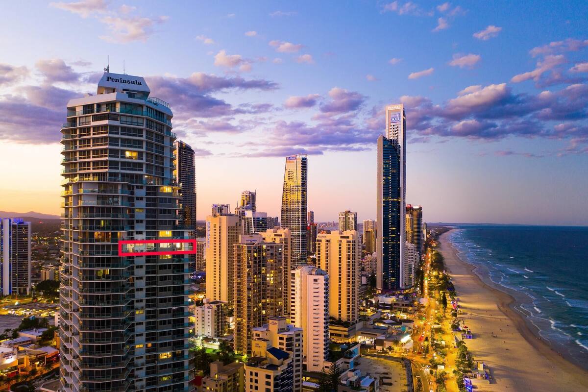 A coastal cityscape with high-rise buildings, a beach, and a clear sky.