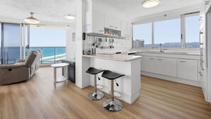 A modern kitchen with a central island, bar stools, and a view of the ocean. - Peninsula Resort - Private Apartments (Surfers Paradise)