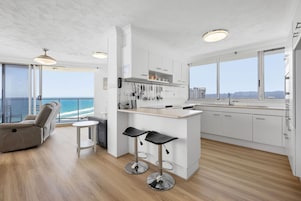 Una cocina moderna con una isla central, taburetes de bar y vistas al océano.