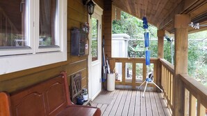 Une véranda en bois avec un banc, une boîte aux lettres et une rambarde.