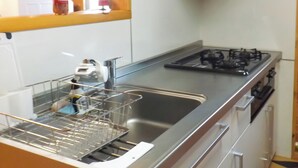 Une cuisine équipée d’un évier en acier inoxydable, d’un égouttoir et d’une cuisinière à gaz.