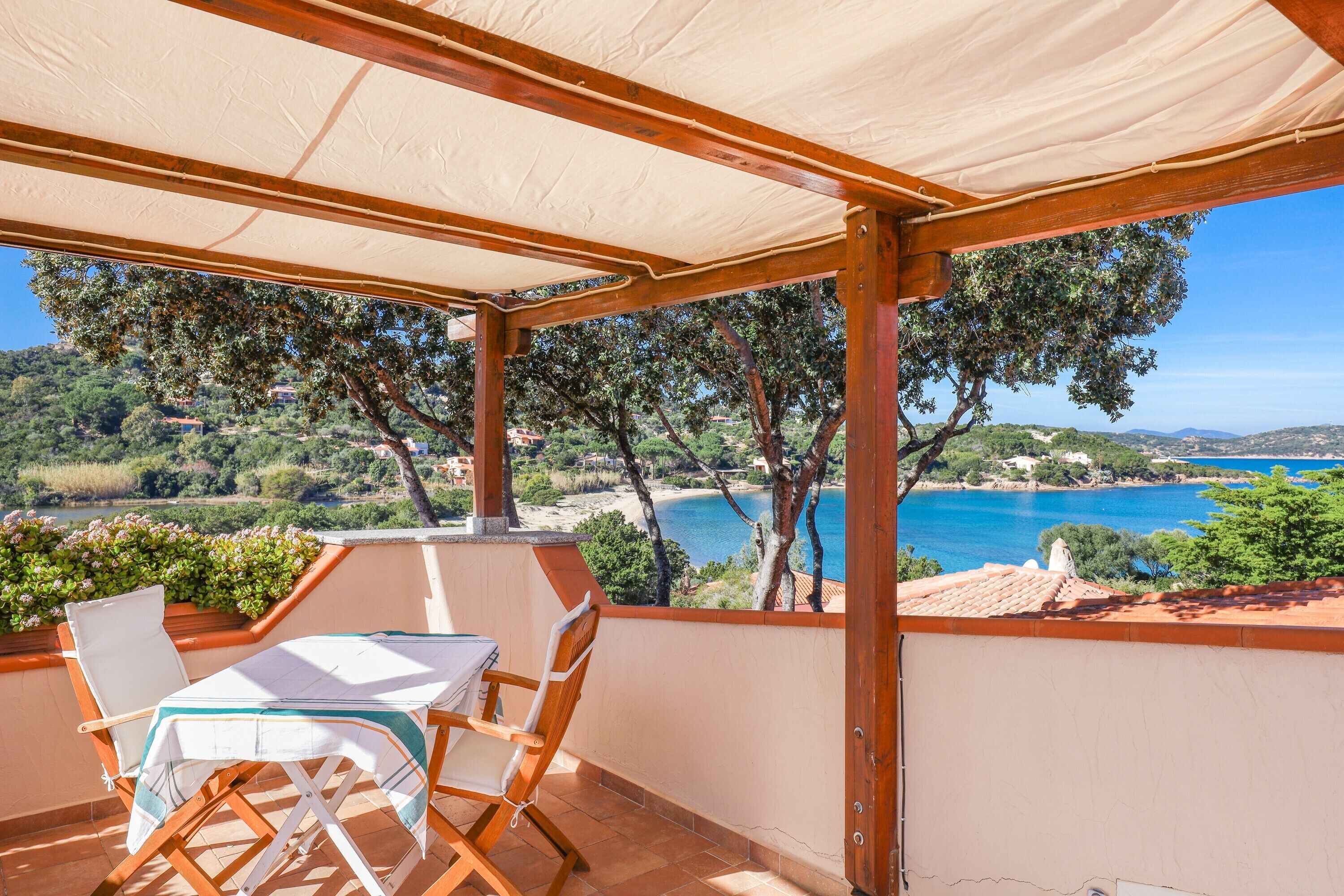 Un espace extérieur abrité, doté d’une table et de chaises, offrant une vue panoramique sur un paysage côtier pittoresque.