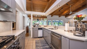 Una cucina moderna con isola centrale, elettrodomestici in acciaio inox e soffitto in legno.