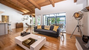 Un'ampia zona giorno con soffitto in legno, un divano moderno e un'ampia finestra con vista sull'esterno.