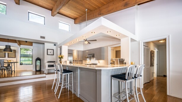Un'ampia cucina con una grande isola, travi in legno al soffitto e vista sull'esterno.