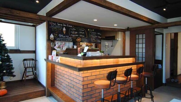 A bar area with a brick counter, bar stools, and a chalkboard menu. - Sapporo Guest House Anne - Hostel (Sapporo)