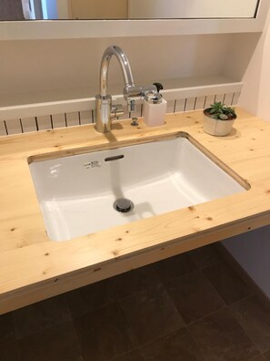A kitchen sink with a wooden countertop, a faucet, and a potted plant. - Sapporo Guest House Anne - Hostel (Sapporo)