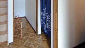 A room with a geometric patterned floor, a wooden staircase, and a blue curtain with a white design. - Sapporo Guest House Anne - Hostel (Sapporo)