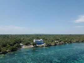 A coastal building with a clear view of the surrounding forest and clear blue waters.