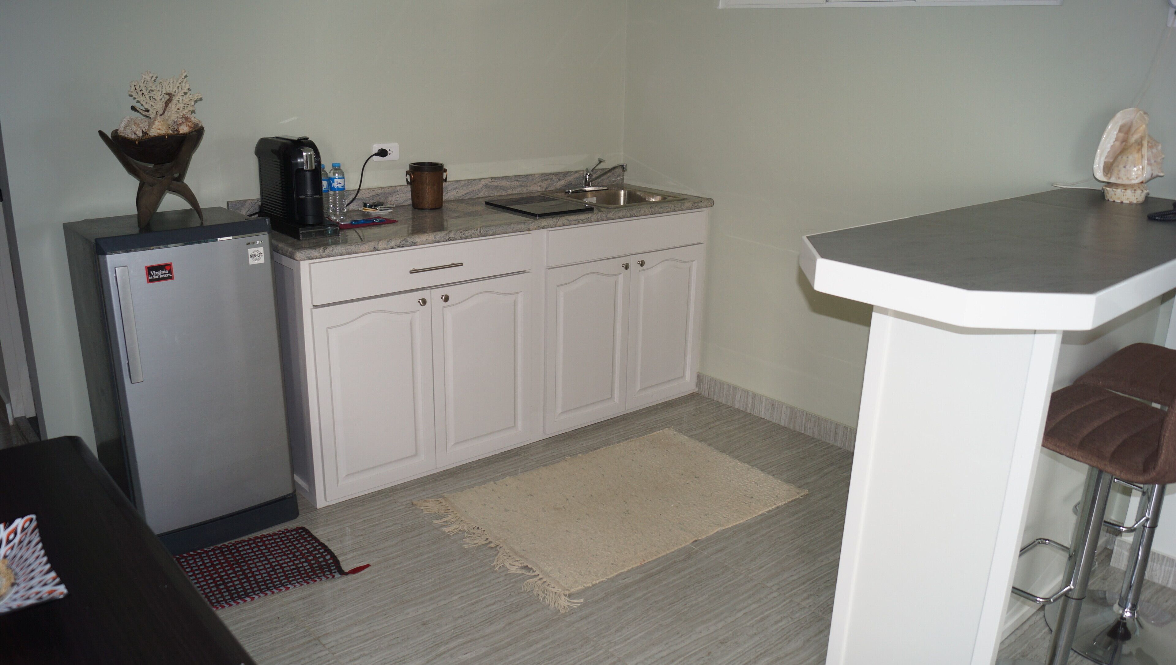 Una cocina compacta equipada con refrigerador, cafetera, lavabo y una pequeña barra.