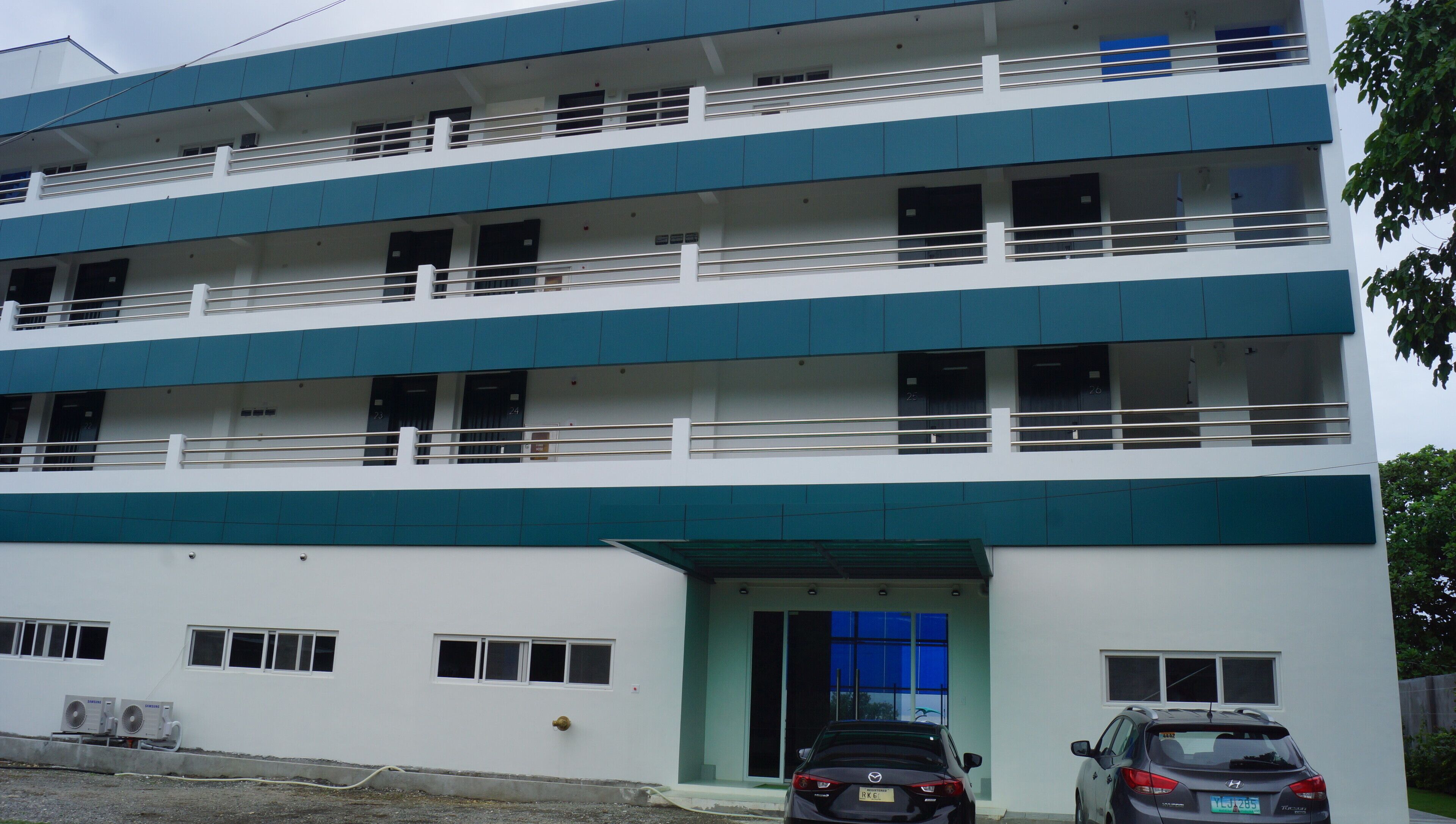 A multi-story building with a flat facade, balconies, and a gated entrance.