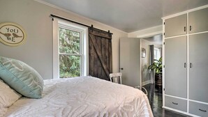 A bedroom with a large bed, a window with curtains, a wardrobe, and a wall decoration. - Charming Dairy Farm Home in Indiana Amish Country (Shipshewana)