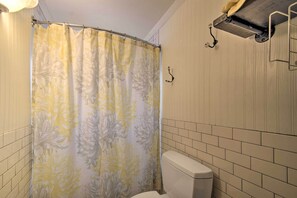 A bathroom with a shower curtain featuring a floral pattern, a toilet, and a towel rack mounted on the wall. - Charming Dairy Farm Home in Indiana Amish Country (Shipshewana)