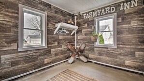A room with rustic wooden walls, a ceiling fan, and a window with a view of a house. - Charming Dairy Farm Home in Indiana Amish Country (Shipshewana)
