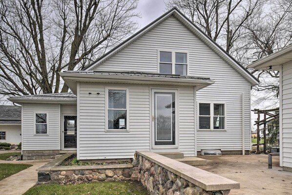 A single-story house with a stone foundation, a front porch, and a small garden area. - Charming Dairy Farm Home in Indiana Amish Country (Shipshewana)