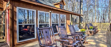 A wooden deck with outdoor seating and large windows.
