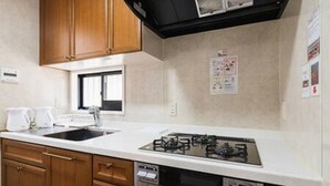 Eine kleine Küche mit Holzausstattung, einem Gasherd, einem Backofen und einer Mikrowelle.