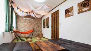 Ein gemütliches Zimmer mit einer Hängematte, zwei Sofas, einem Holztisch und einer Ziegelwand.