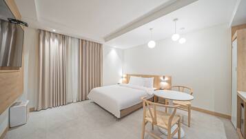 Une chambre d’hôtel avec un lit, une table de chevet et une petite table ronde avec des chaises.