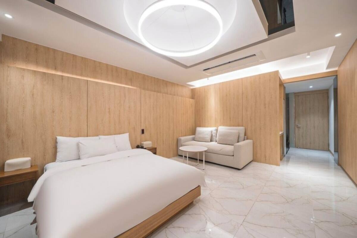 A modern bedroom with a large bed, a sofa, and a small table.