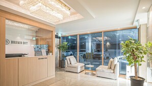 A modern reception area with a wooden counter, a chandelier, and a seating area with two sofas and a small table. - BrownDot Hotel Bong-Duk (Daegu)
