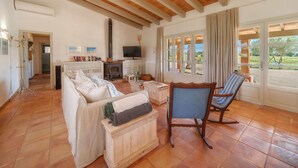 A cozy living room with a sofa, a wooden chair, a fireplace, and a television.