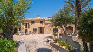 A Mediterranean-style villa with a courtyard, outdoor seating, and a mix of stone and stucco architecture.