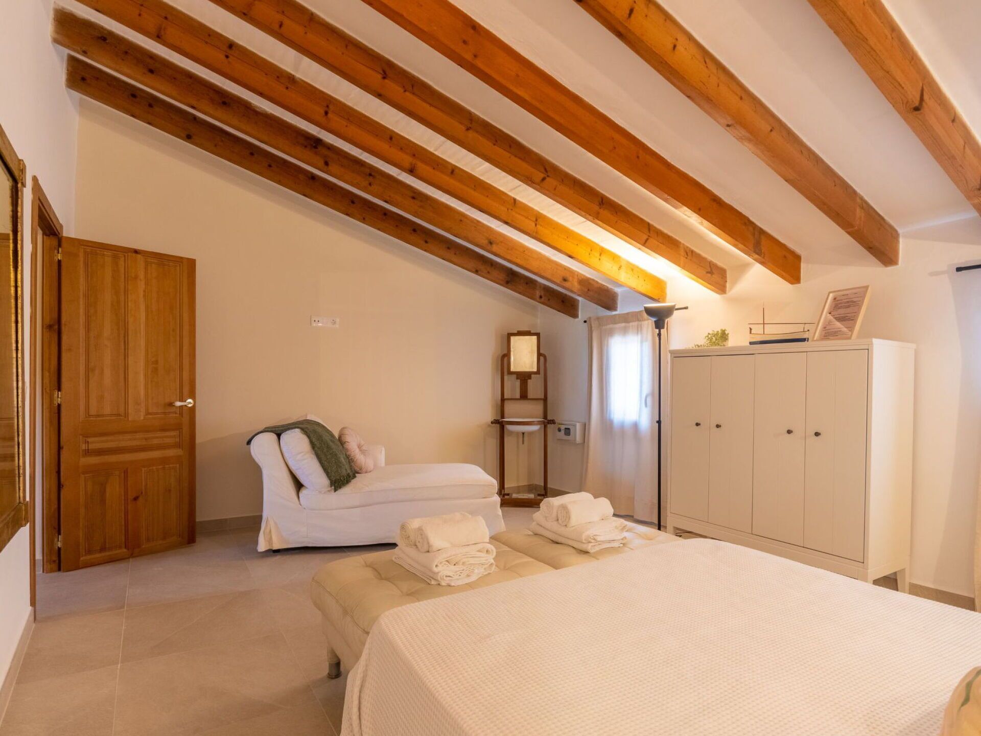 Une chambre à coucher avec un lit, un banc, une armoire et une porte.