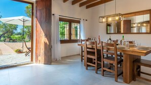 A dining area with a wooden table and chairs, a large window with curtains, and a view of the outdoors.