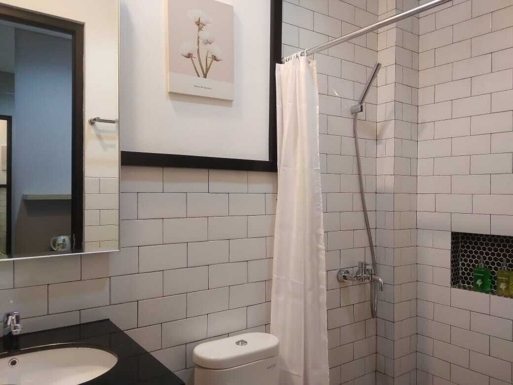 A bathroom with a white sink, a toilet, a shower with a curtain, and a framed picture on the wall.