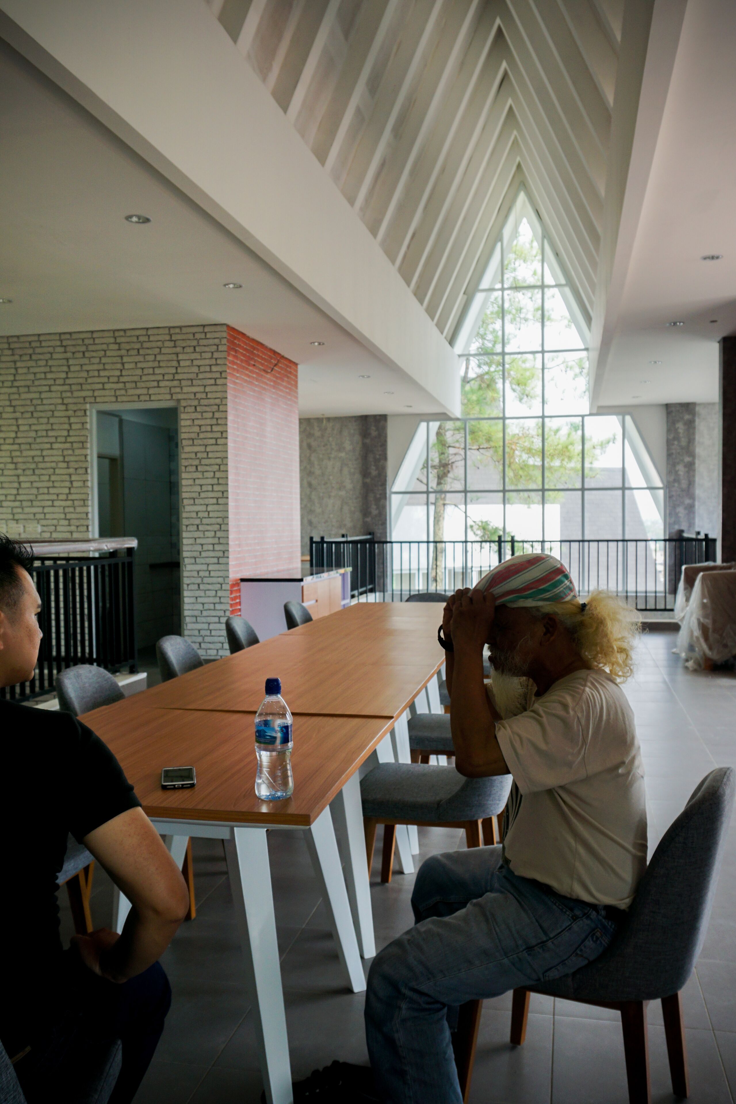 A modern conference room with a long table, chairs, and a brick accent wall.