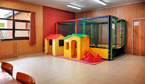 A play area with a trampoline and two small playhouses.