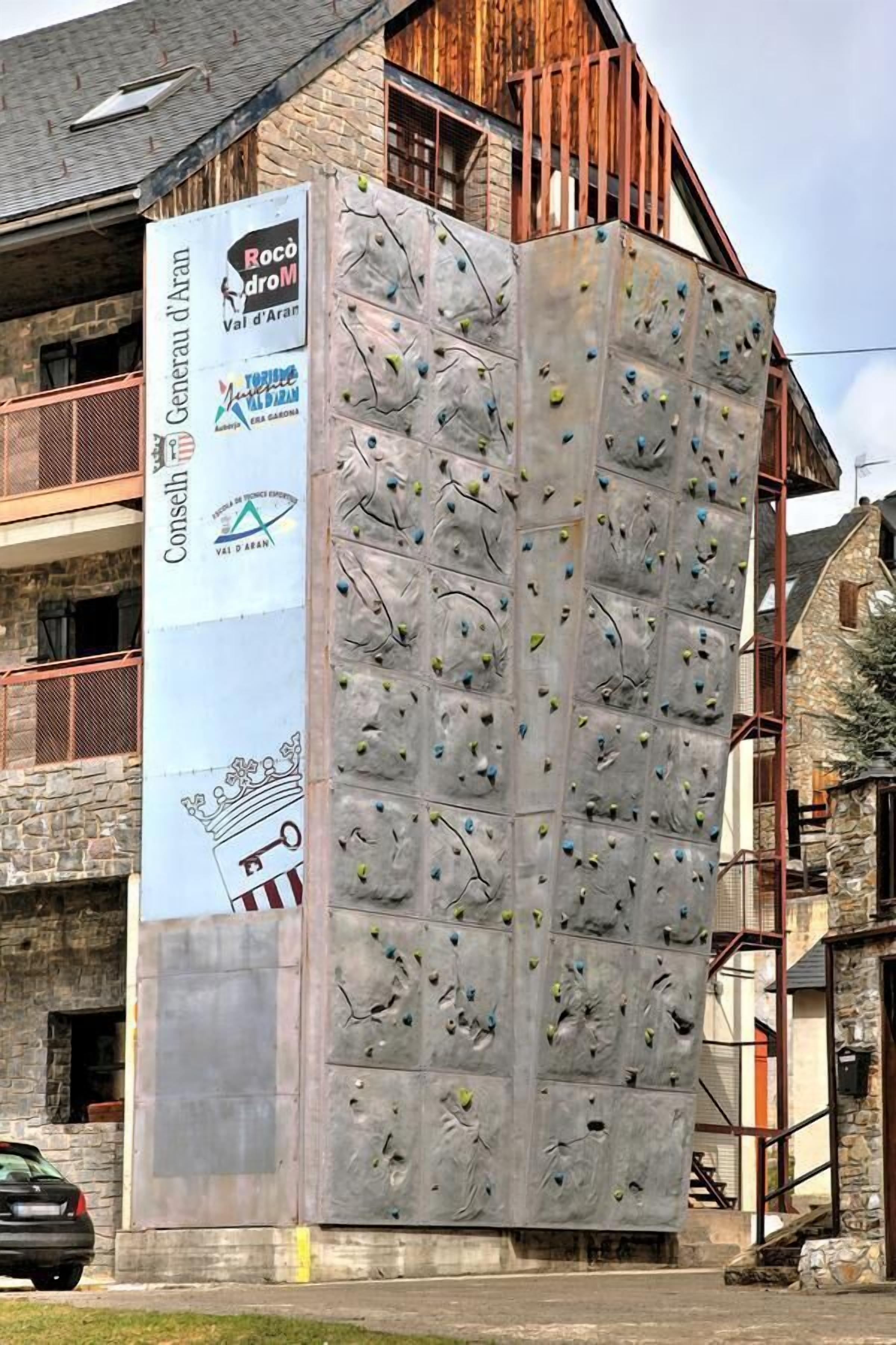 A climbing wall with a vertical banner advertising Rocco d'oro Val d'Aran.