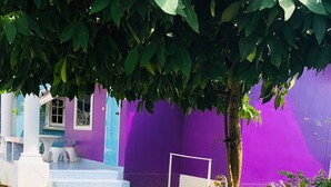 Un jardin agrémenté de statues colorées, avec un bâtiment violet en arrière-plan.