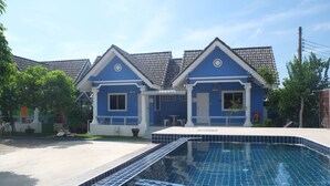 Une maison bleue avec une piscine devant.